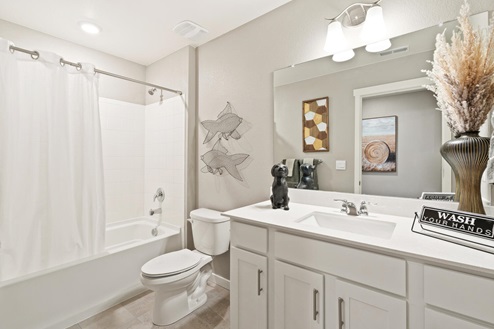 Bathroom with tub and shower combo, sink, full size mirror and white cabinets