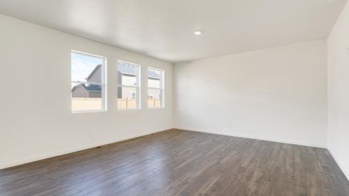 living room with a window, white walls and brown wood floor