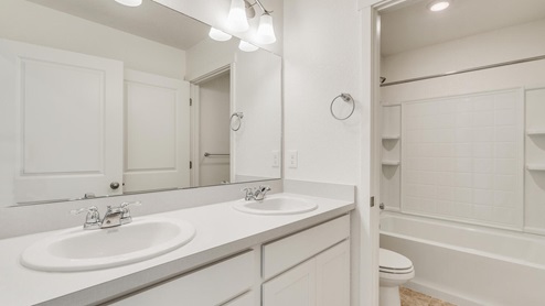 white cabinet bathroom with toilet and tub in a separate room
