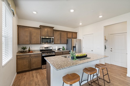 spacious kitchen with kitchen island, pantry and three barstools