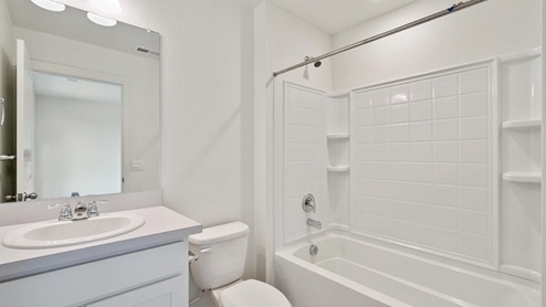 bathroom with white cabinets and separate space for the toilet