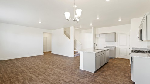 spacious living and kitchen with white walls and wood floor