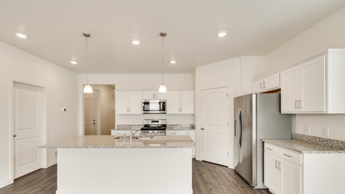 white cabinet kitchen with an island, window, ceiling light and stainless steel appliances
