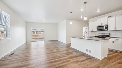 open space kitchen and living room with wood flooring throughout