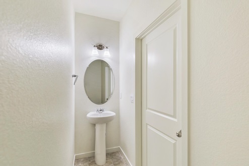 half bathroom with a sink and round mirror