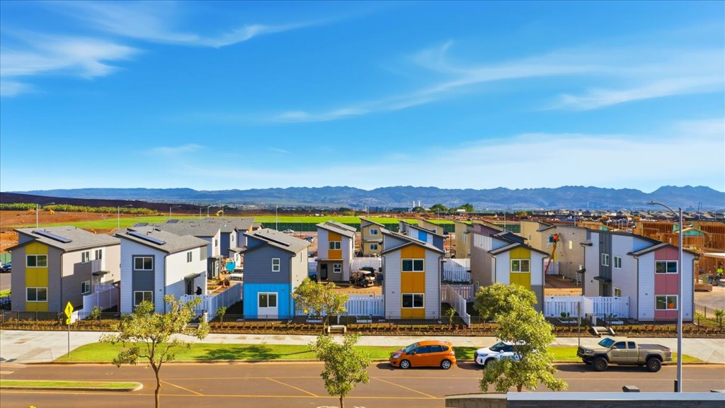Exterior drone photo two story homes pink yellow blue and green