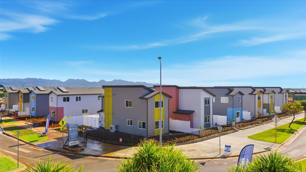 Exterior drone photo two story homes pink yellow blue and green