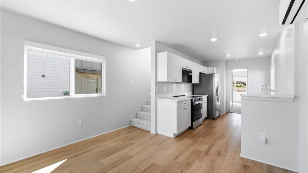 Interior kitchen with stainless steel appliances open to stairs and living room