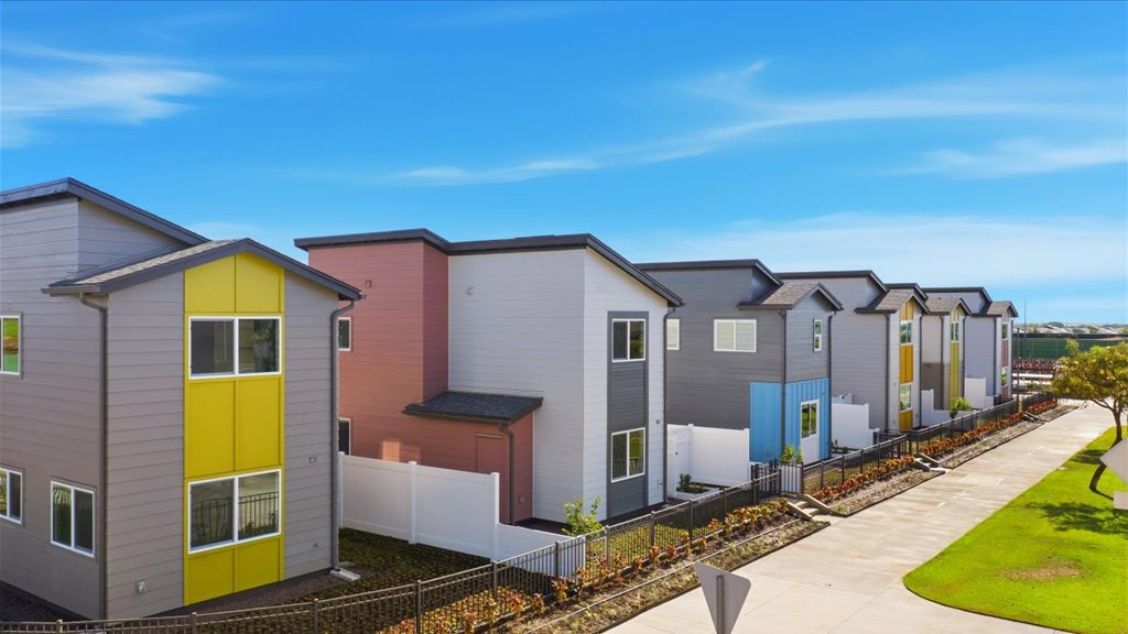 Exterior drone image two story homes yellow blue green and pink