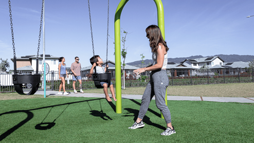 Amenity park swing set with woman pushing child on swings