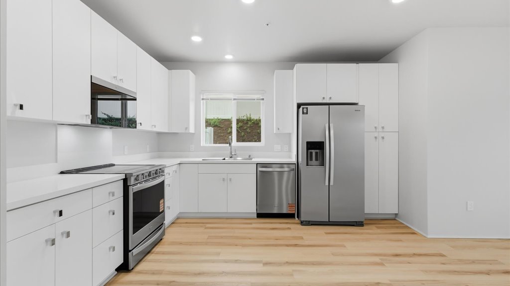 Interior kitchen stainless steel appliances open to living room