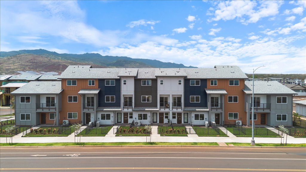 Exterior three story building with red and gray wood cladding and one car garages