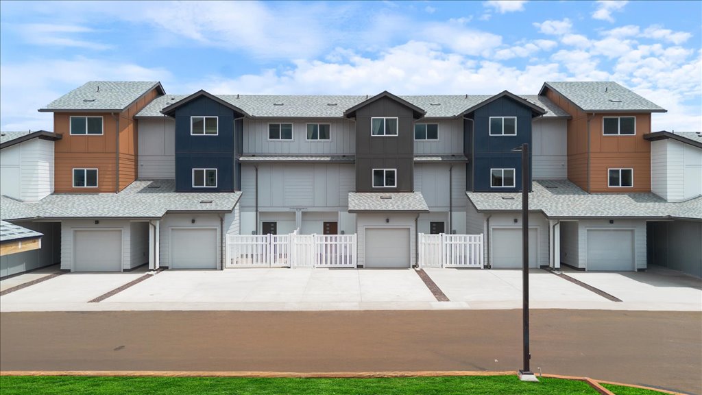 Exterior three story building with red and gray wood cladding and one car garages