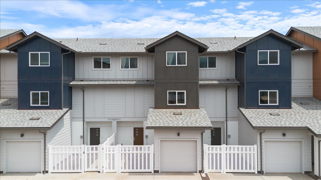 Exterior three story building with red and gray wood cladding and one car garages