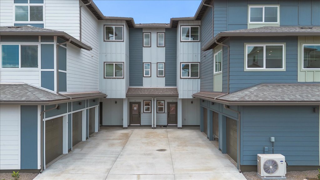 Exterior three story building with blue wood cladding and motorcross garages