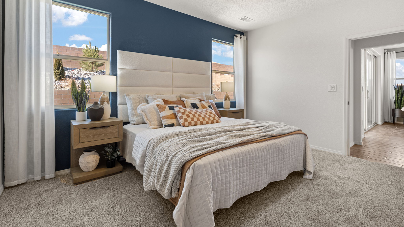 Primary bedroom features ample space, double windows, soft carpet, a stylish walk-in closet, and a private ensuite bath