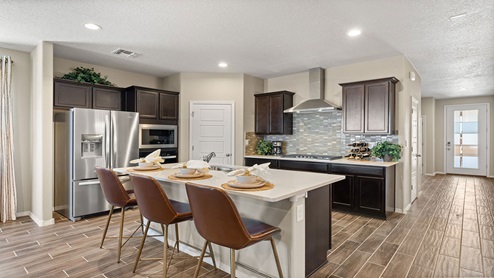 kirchen with brown cabinets, island, stainless steel appliances, and granite countertops