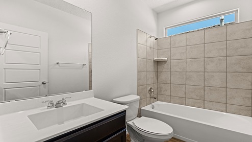 secondary hallway bathroom with dual vanity sink and tub/shower combo with tile walls