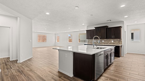 kitchen with dark brown cabinets, granite countertops, and island with kitchen sink