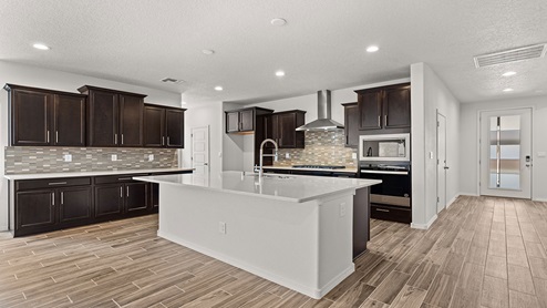 kitchen with dark brown cabinets, granite countertops, and island with kitchen sink