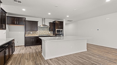 kitchen with dark brown cabinets, granite countertops, and island with kitchen sink