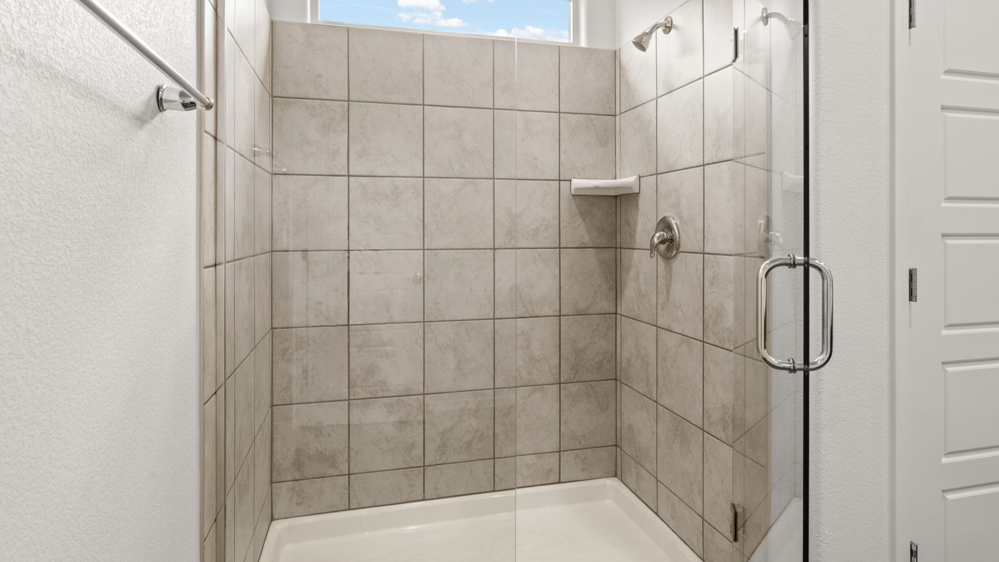 Primary bathroom with dual sinks, standing shower with tile surrounds, and tile floor