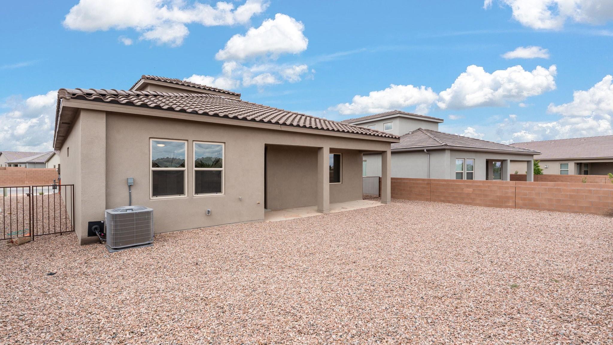 Bliss back exterior with backyard gravel landscaping and covered patio
