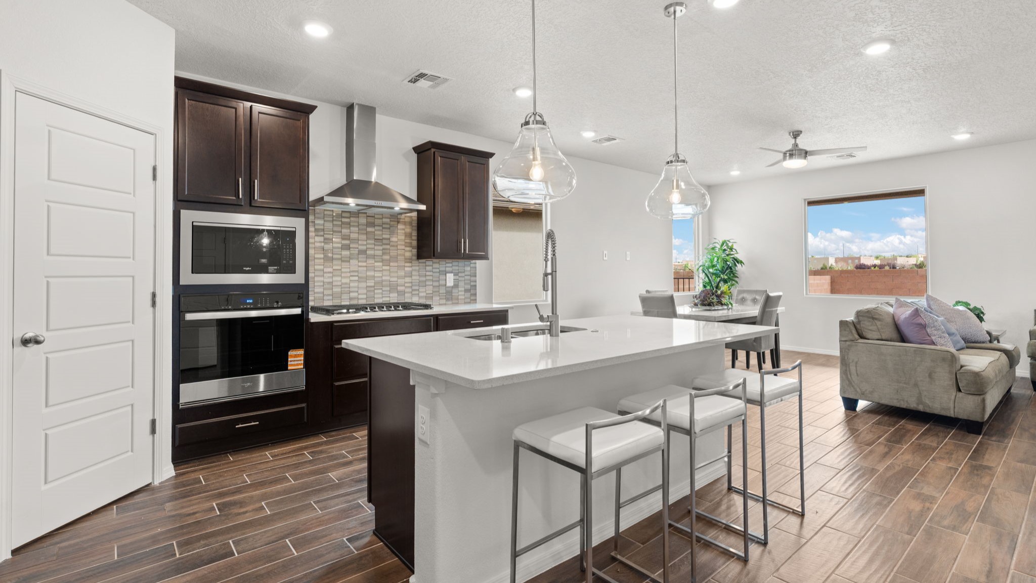 Bliss kitchen with brown cabinets, tile floors, kitchen island with sink, and granite countertops.