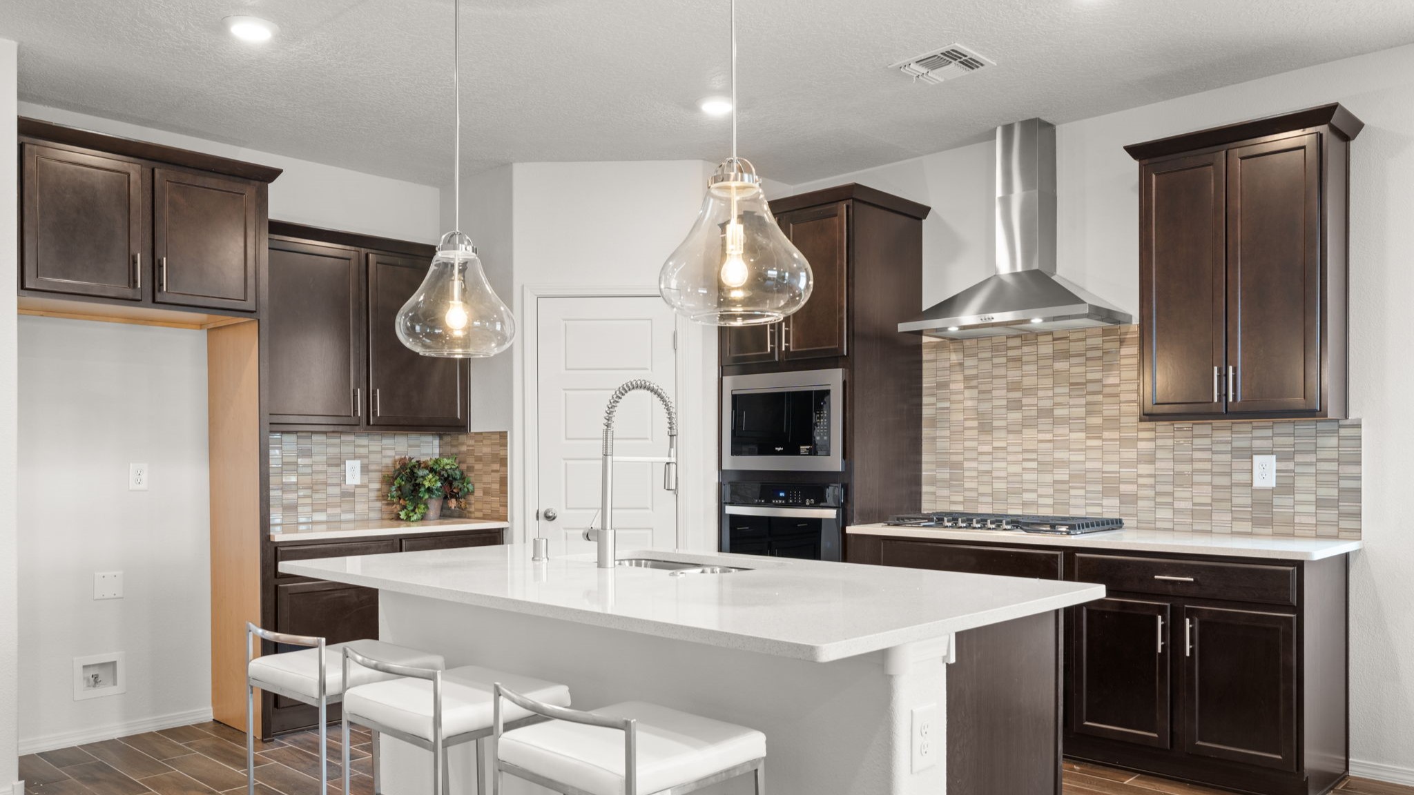 Bliss kitchen with brown cabinets, tile floors, kitchen island with sink, and granite countertops.