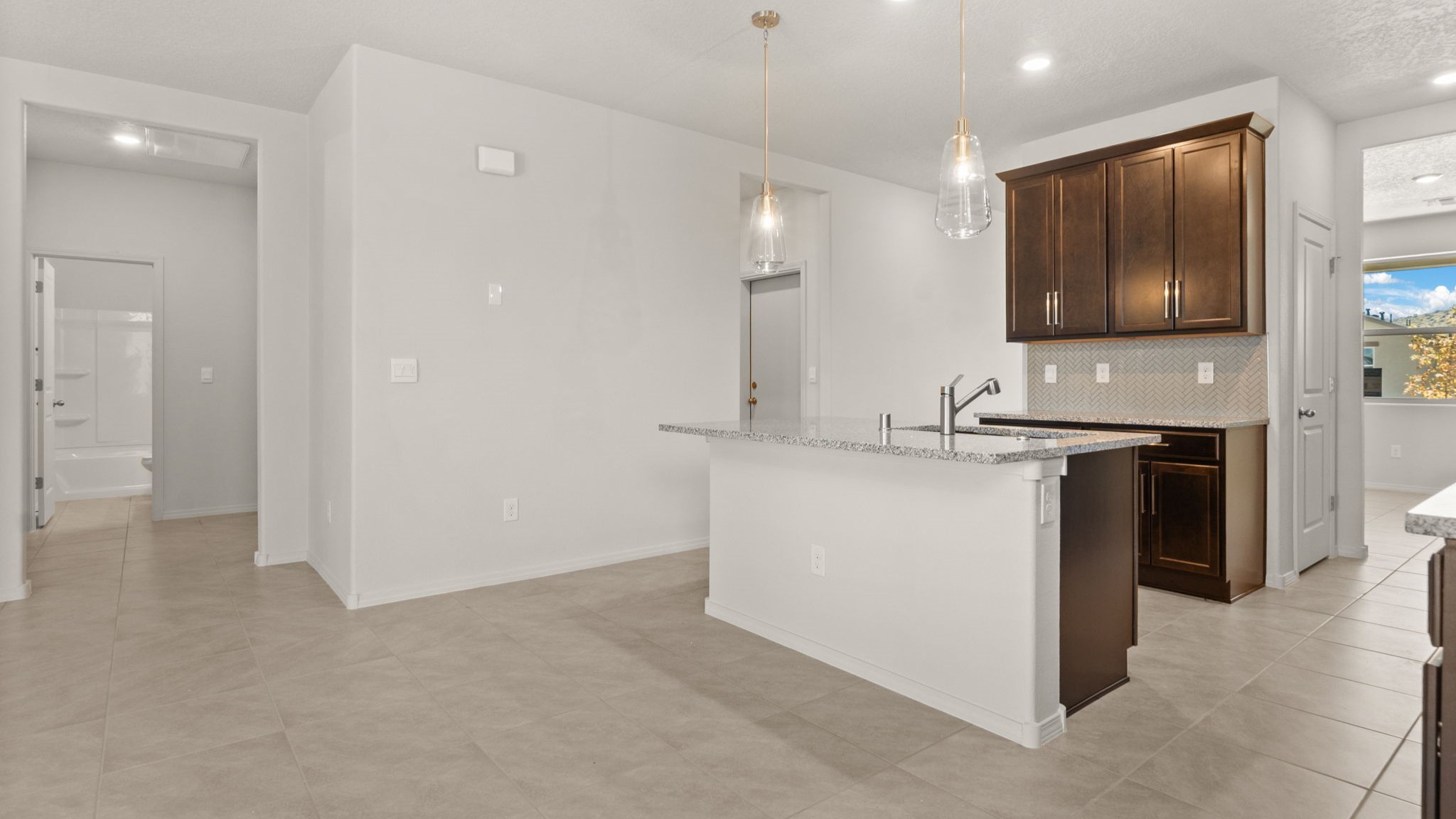 Kitchen island with sink offering prep space, seating, pantry and modern finishes at Vista Grande