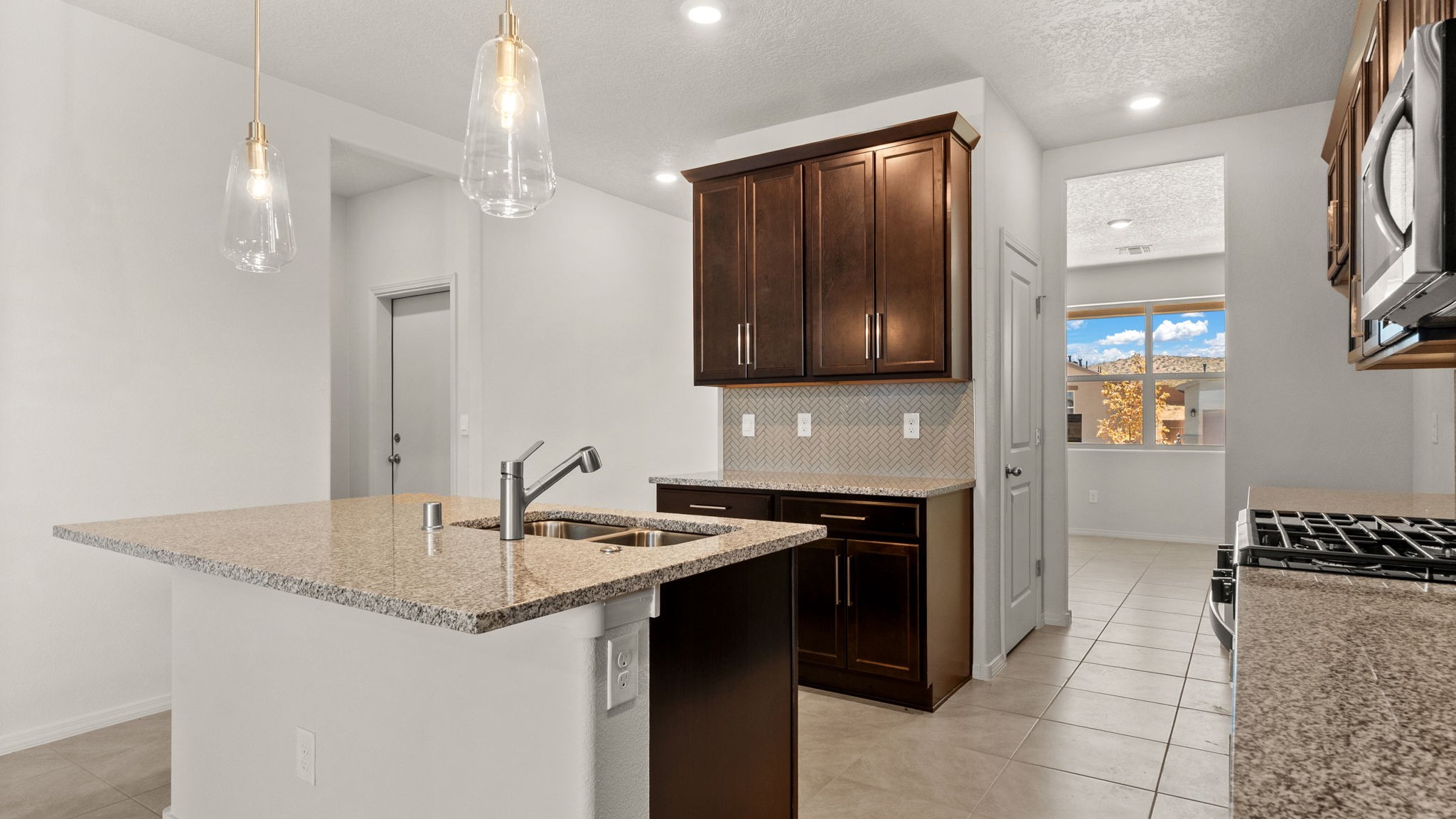 Kitchen island with sink showcasing surface space, pantry, appliance suite included in a contemporary layout at Vista Grande