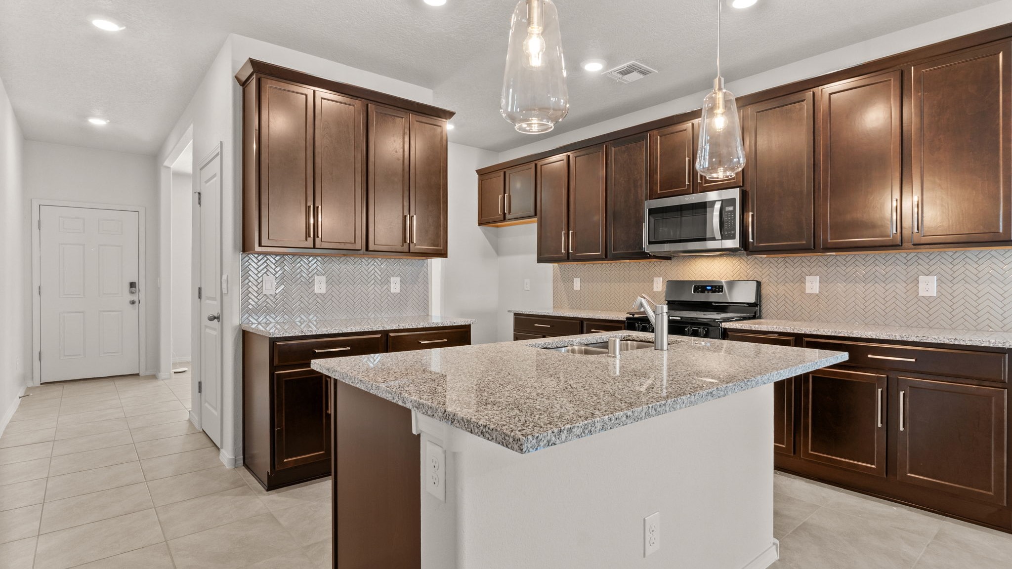 Kitchen island with sink, seating centered in the gathering space, and designed for daily use at Vista Grande