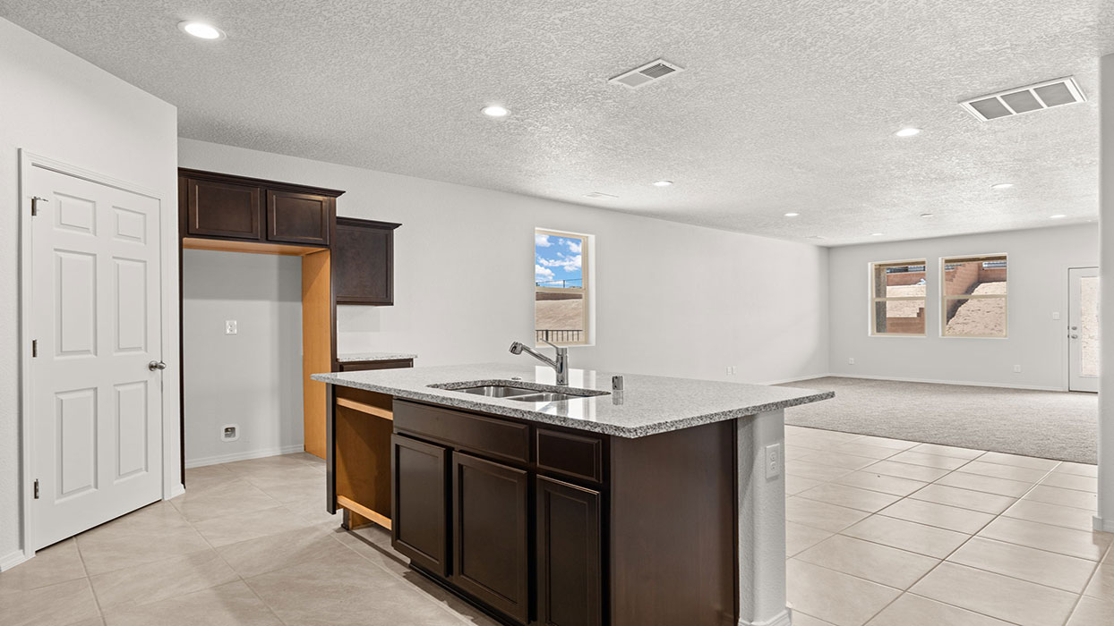 Kitchen with tile floors and granite countertops. Center island with sink and corner pantry.