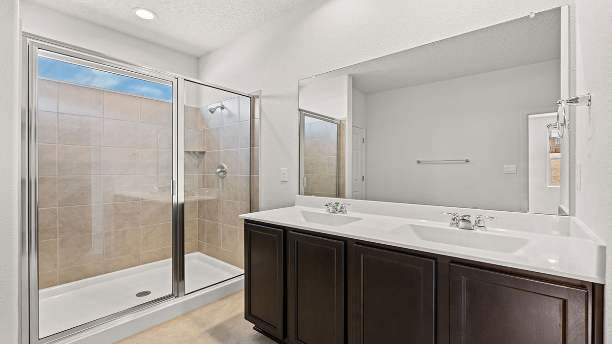 Primary bathroom with dual vanity with cabinet, tile floor, and standing shower with glass door
