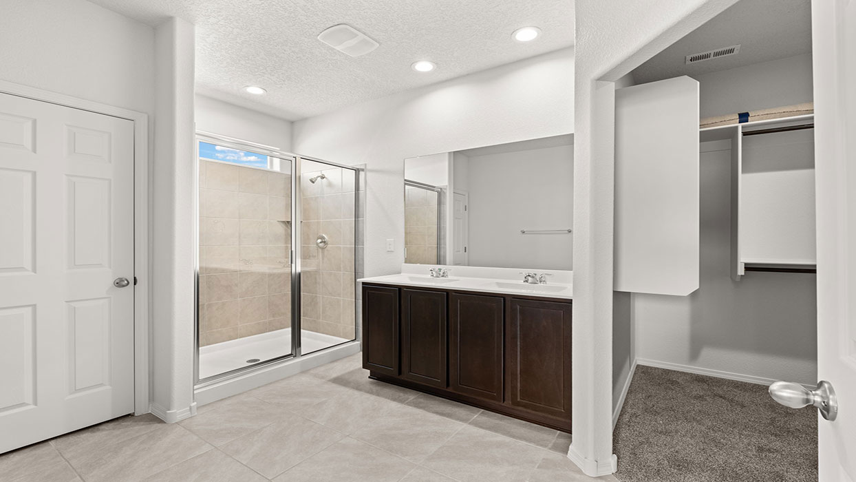 Primary bathroom with dual vanity with cabinet, tile floor, and standing shower with glass door