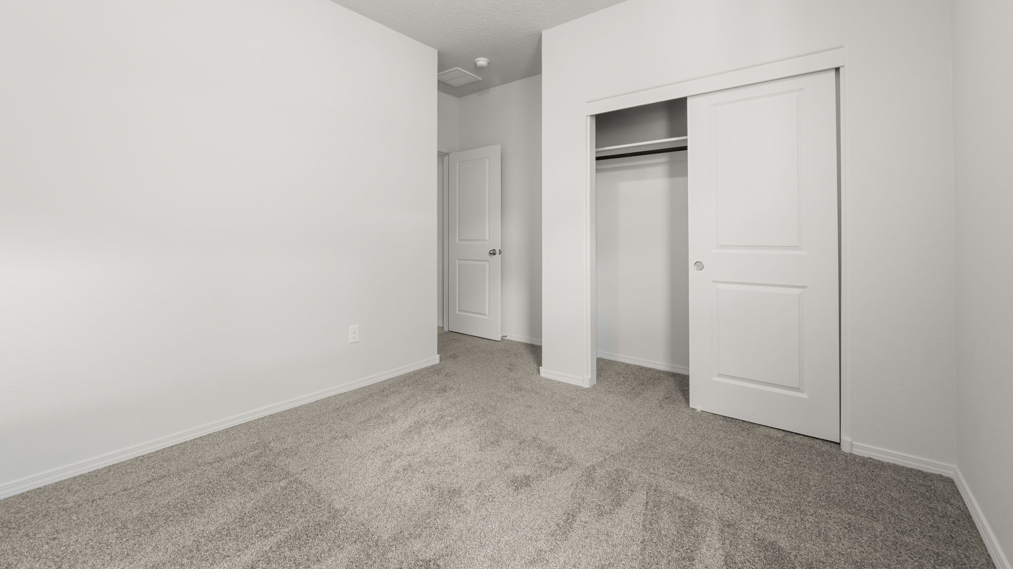 Bedroom with white walls, brown carpet, and a closet.
