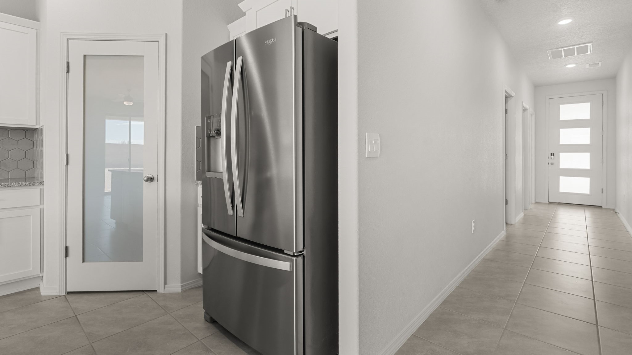 Kitchen featuring white cabinets, stainless steel appliances off the hallway.