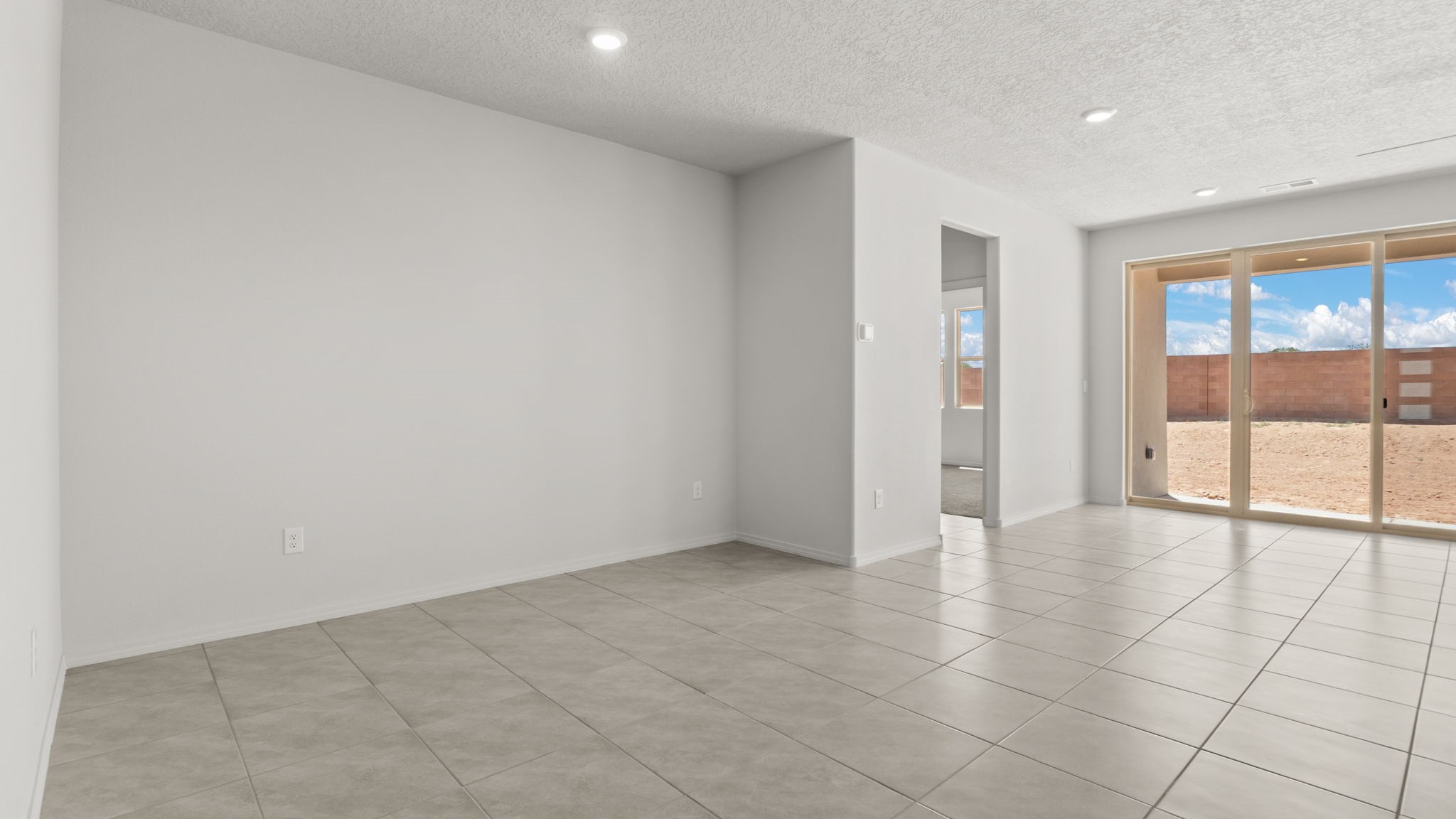 Dining area with white walls, brown tile, and natural lighting.