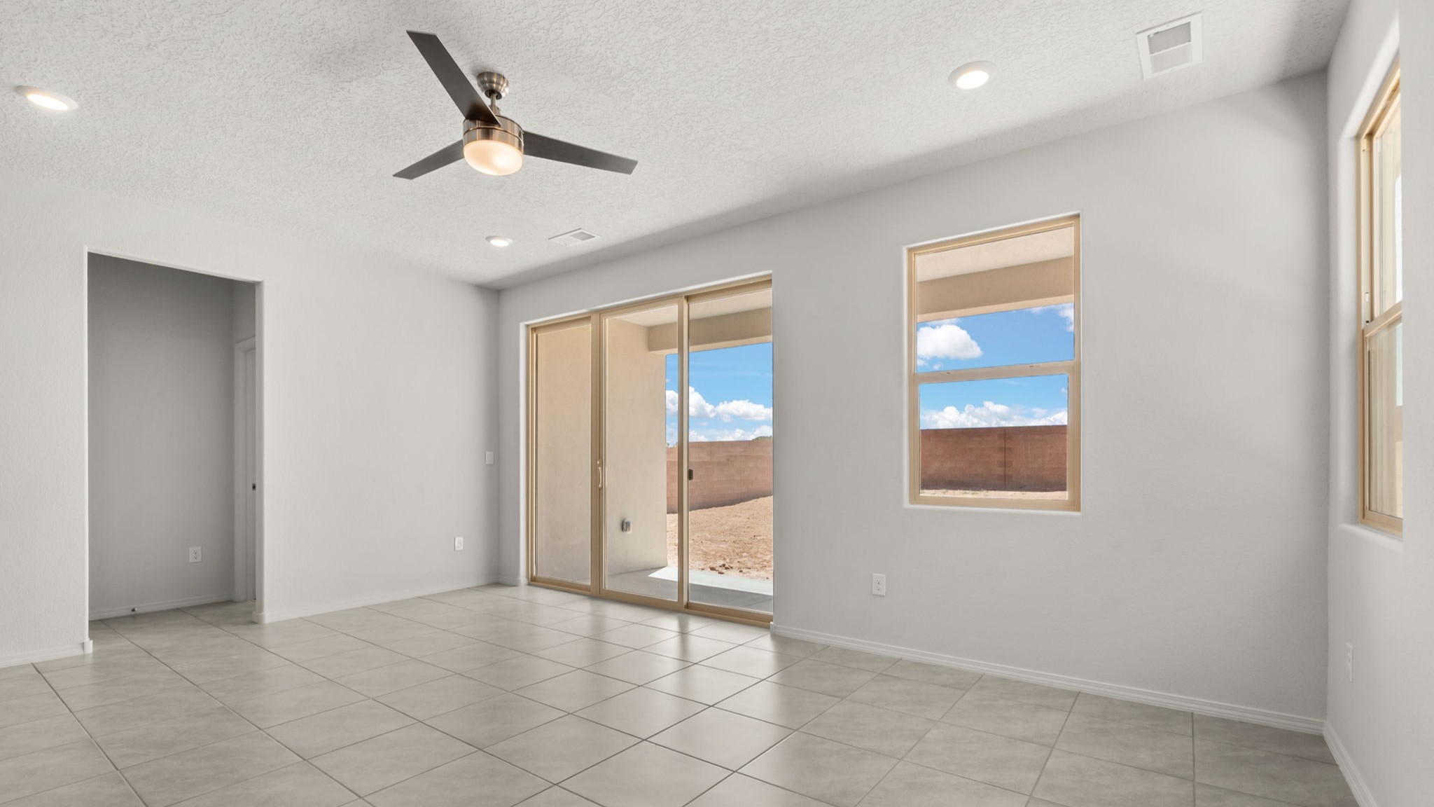 Living area with white walls, brown tile, and a large sliding door,