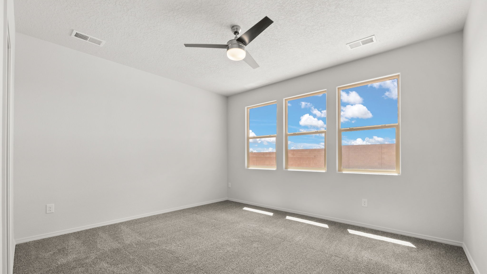Bedroom with white walls, brown carpet, and large windows.