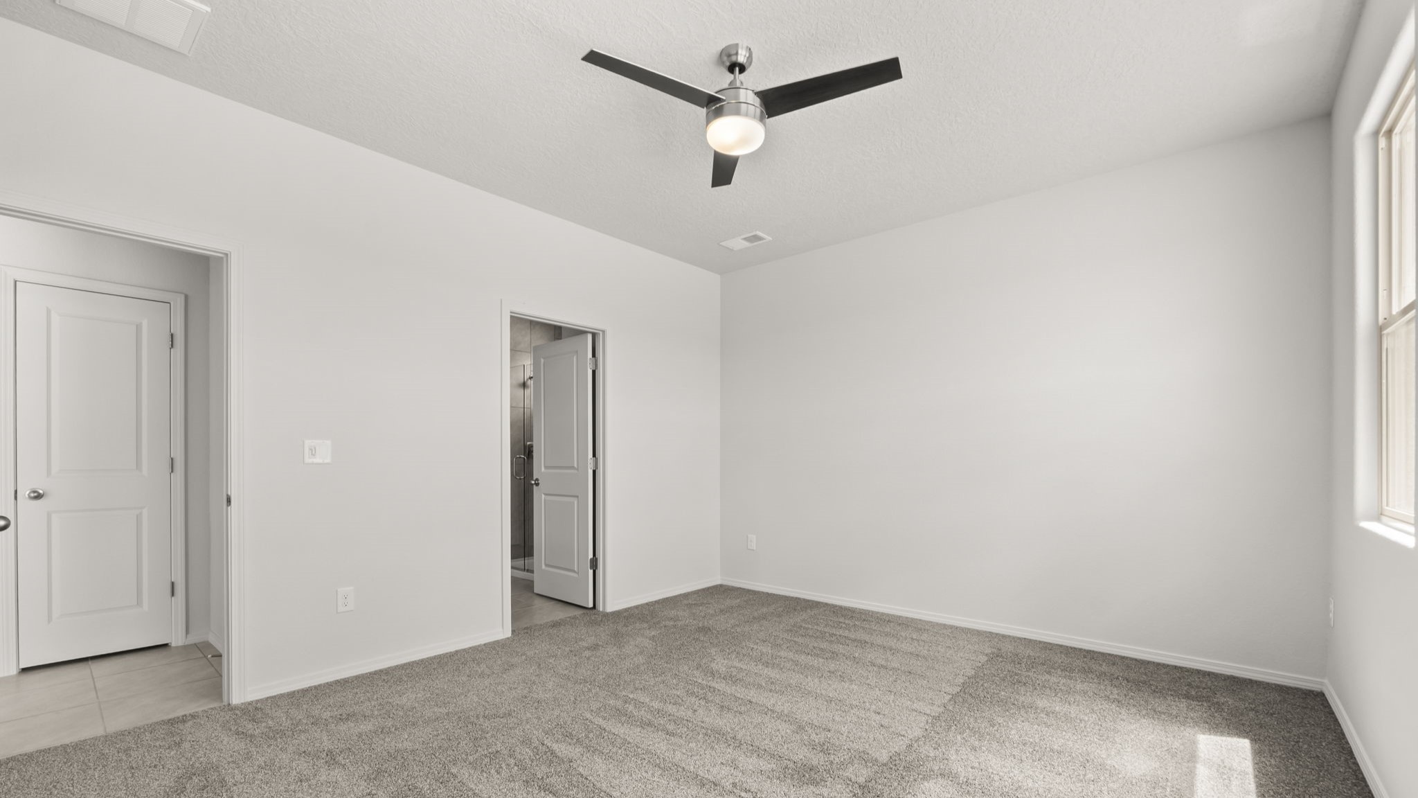 Bedroom with white walls, brown carpet, and a bathroom connected.