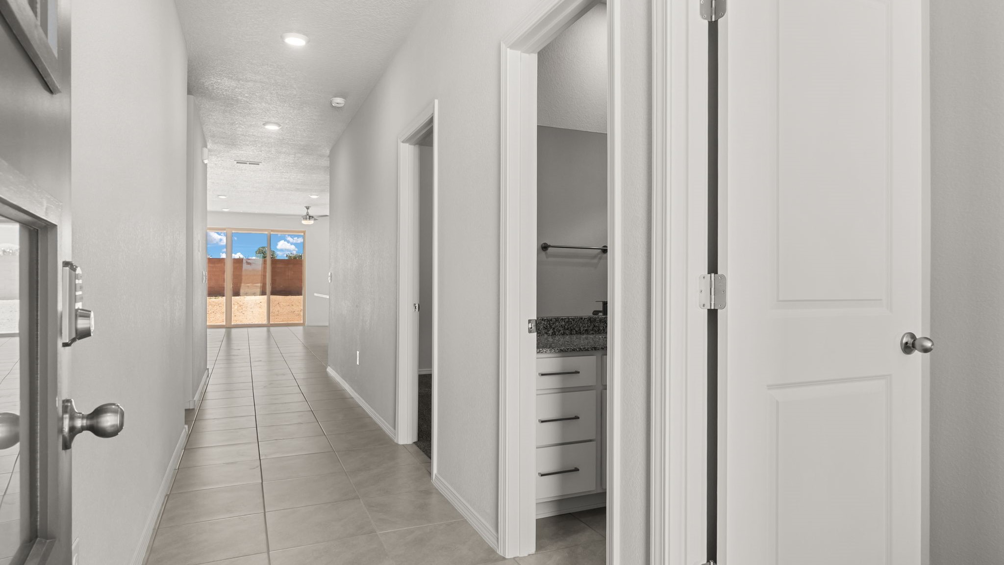 Entryway with white walls, light brown tiles, and doors off the hallway.