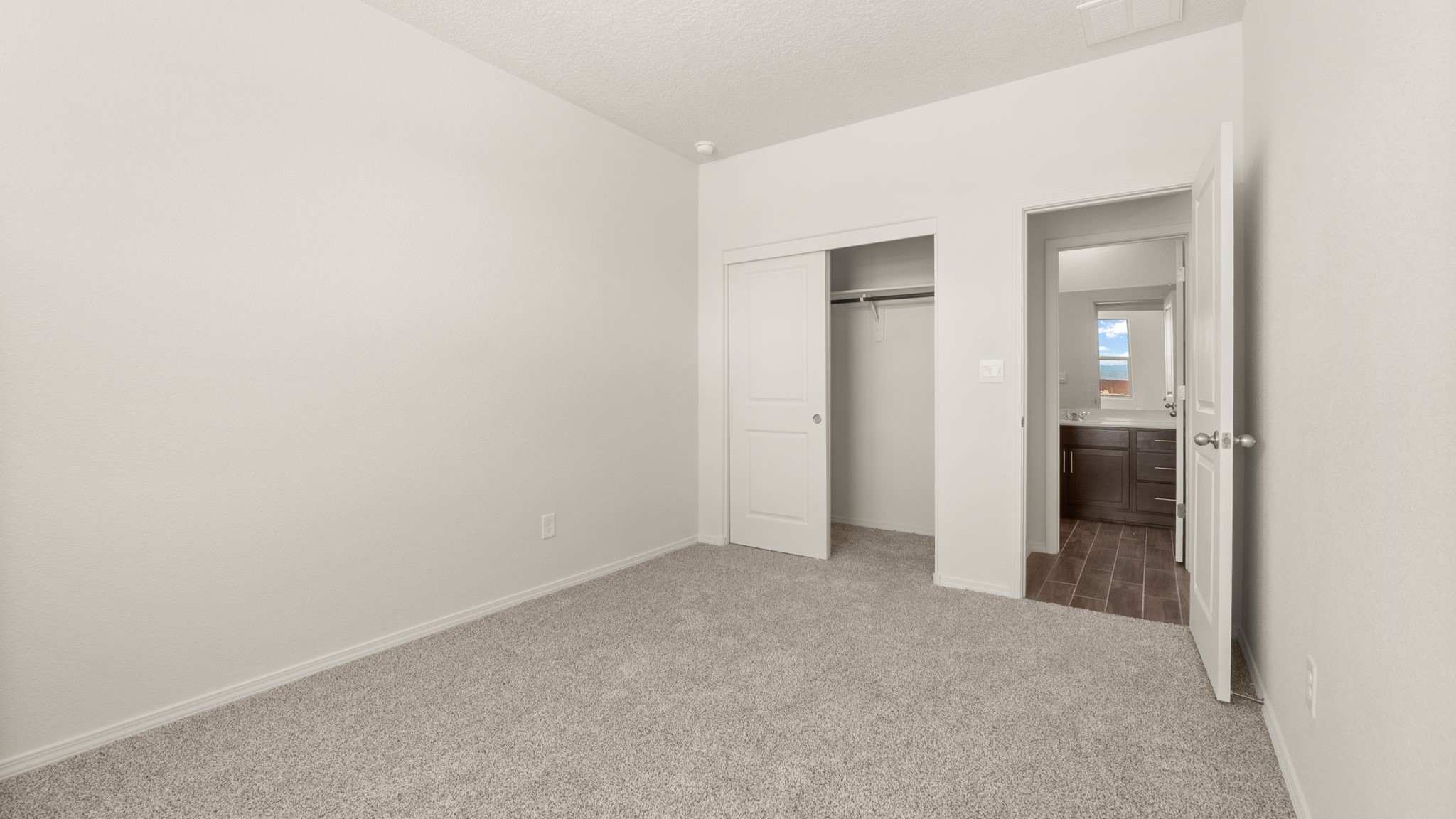 Bedroom with brown carpet, white walls, and a closet.