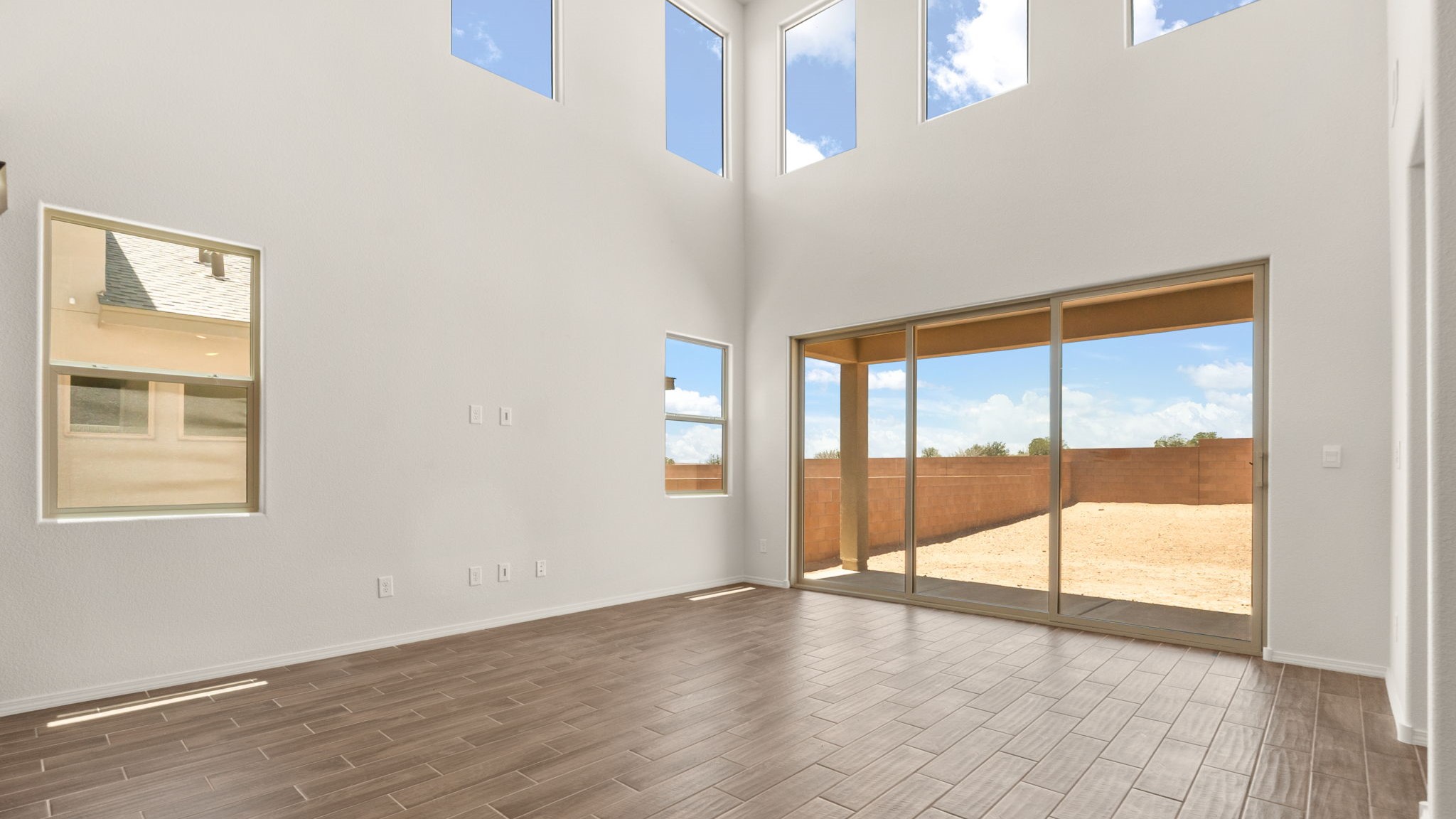 Living room area with brown wood floors, white walls, and a large sliding door..