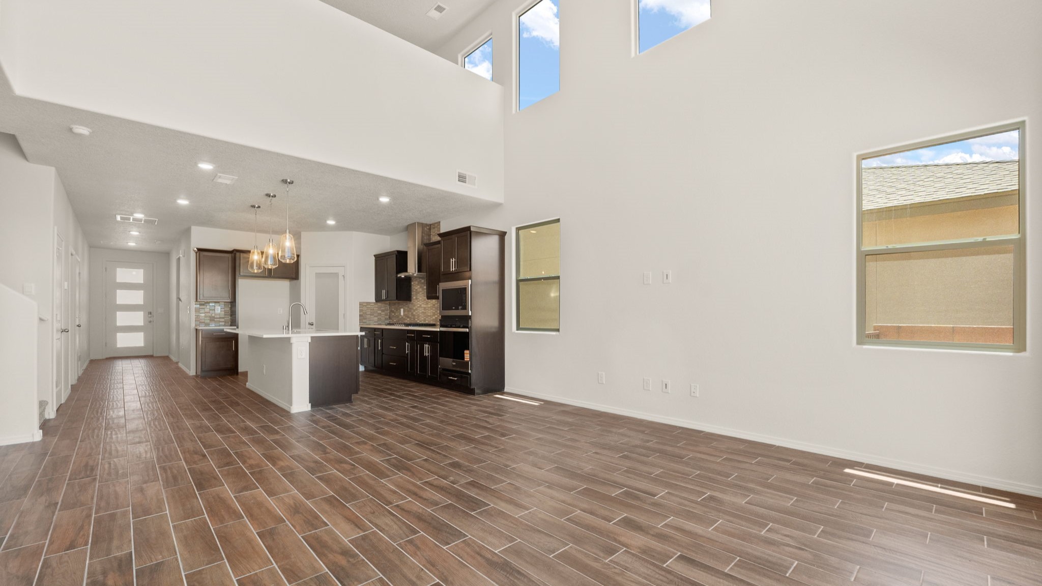 Living room area with brown wood floors, white walls, and a large sliding door..