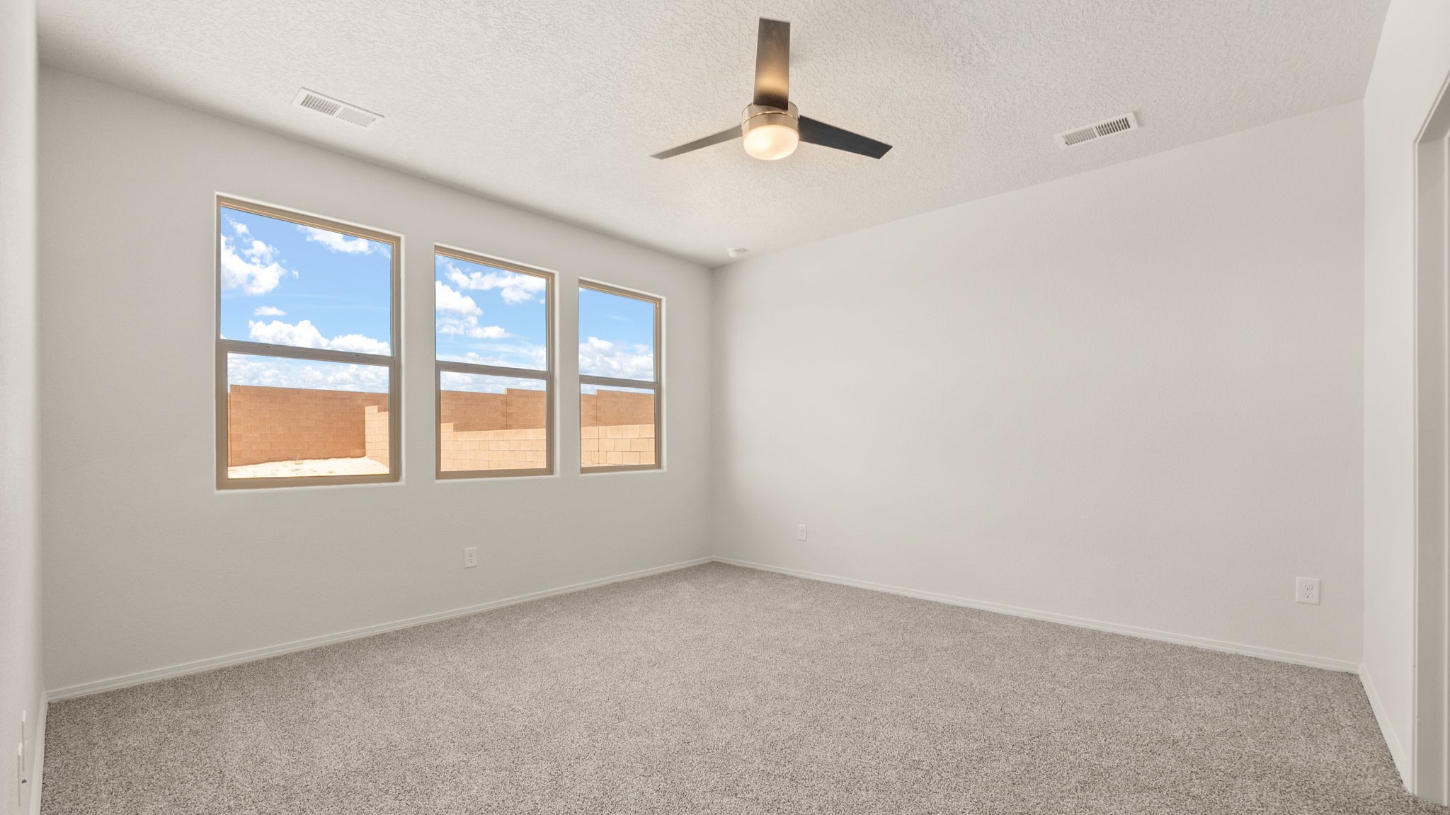 Bedroom with brown carpet, white walls, and a large window.