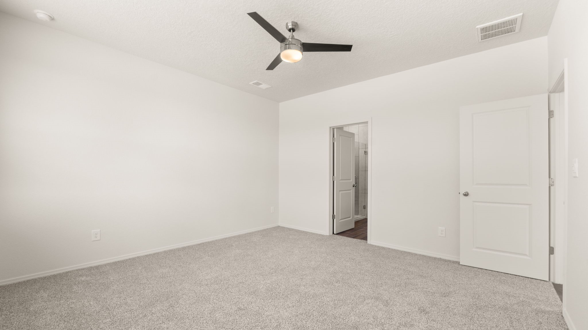 Bedroom with brown carpet, white walls, and a bathroom connected.