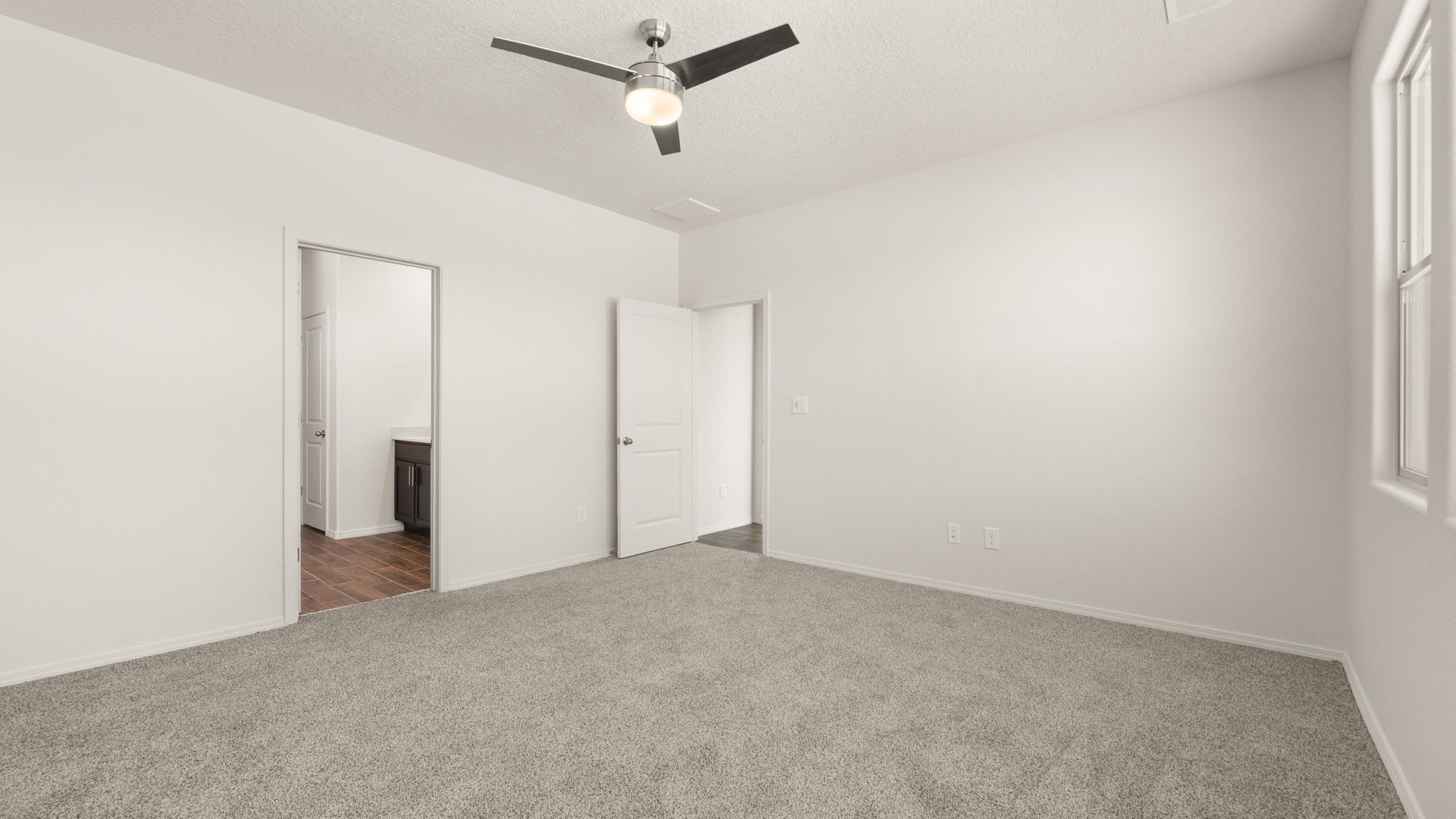 Bedroom with brown carpet, white walls, and a bathroom connected.