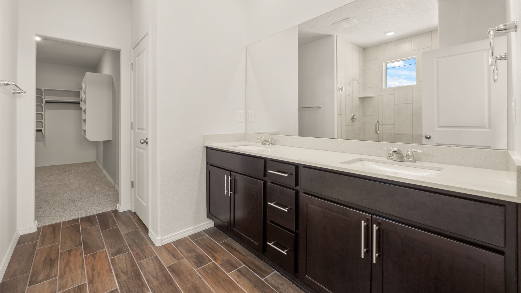 Bathroom with dual sinks, a walk in shower, and a walk in coset.