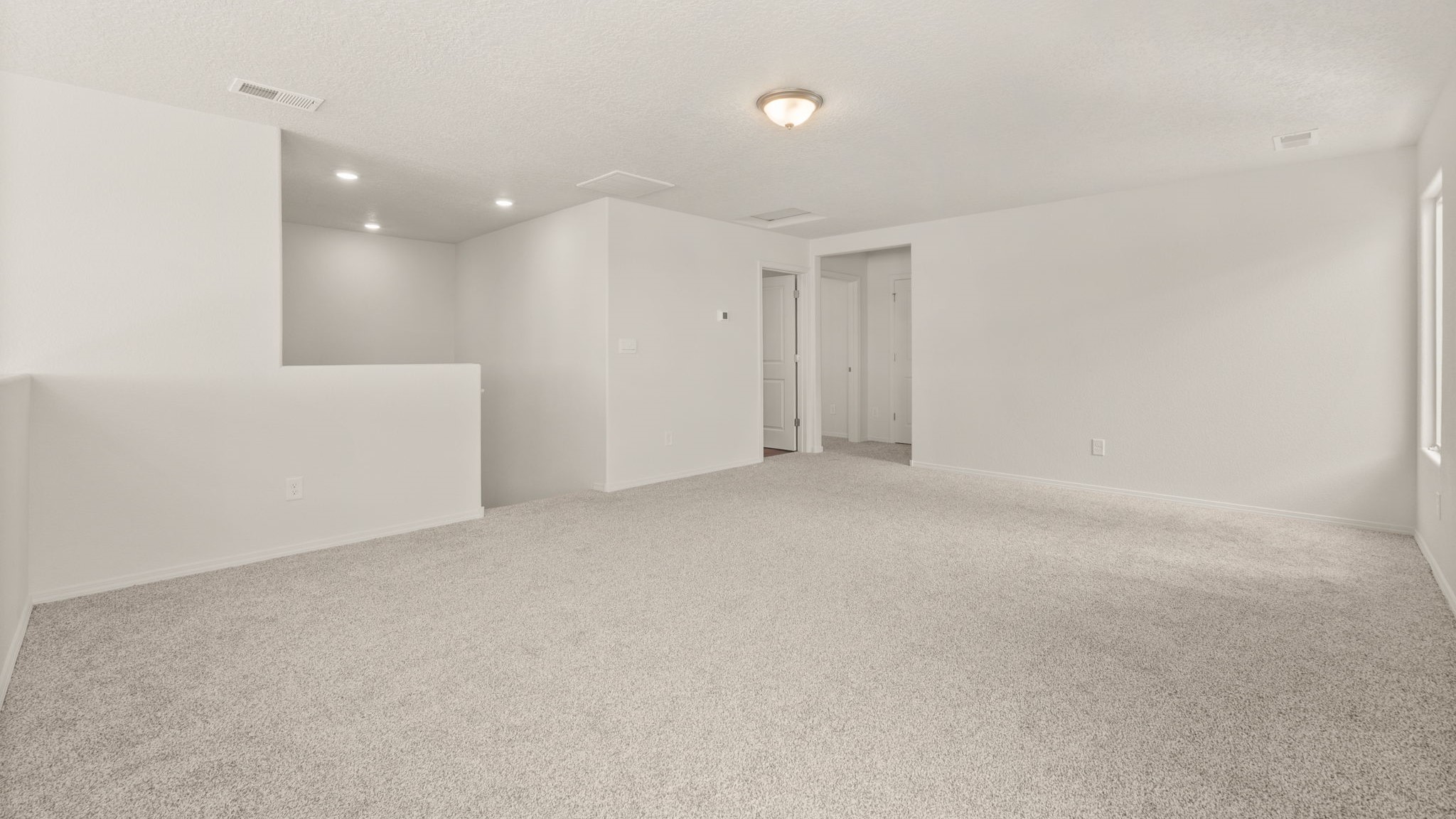 Area at the top of the stairs with brown carpet, white walls, and a bathroom.